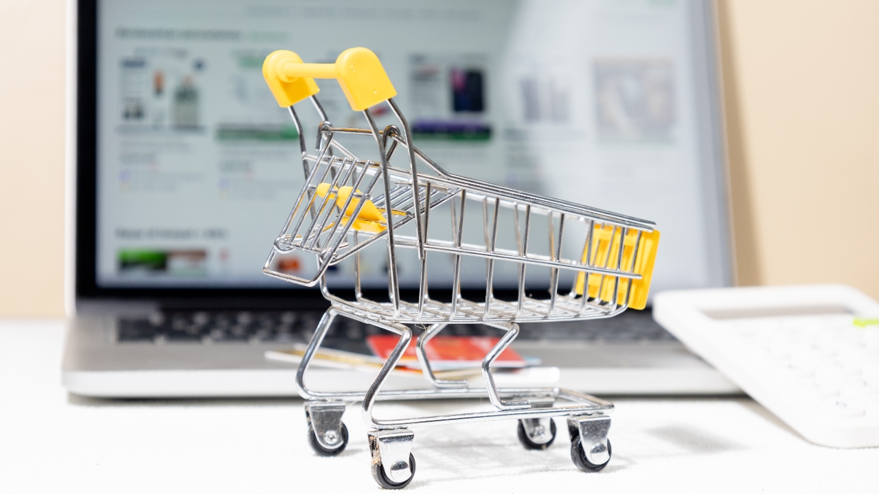 Mala kolica ispred laptopa prikazuju online prodaju i kupovinu preko digitalnih kanala